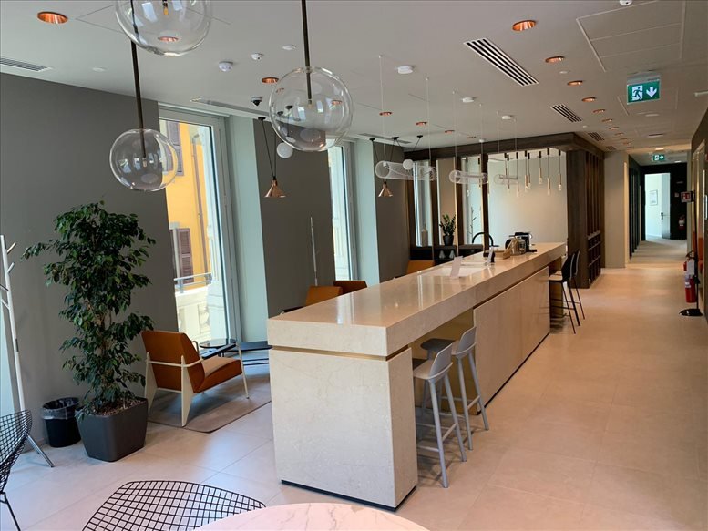 Bright shared office space with white desks, black chairs, and large windows.