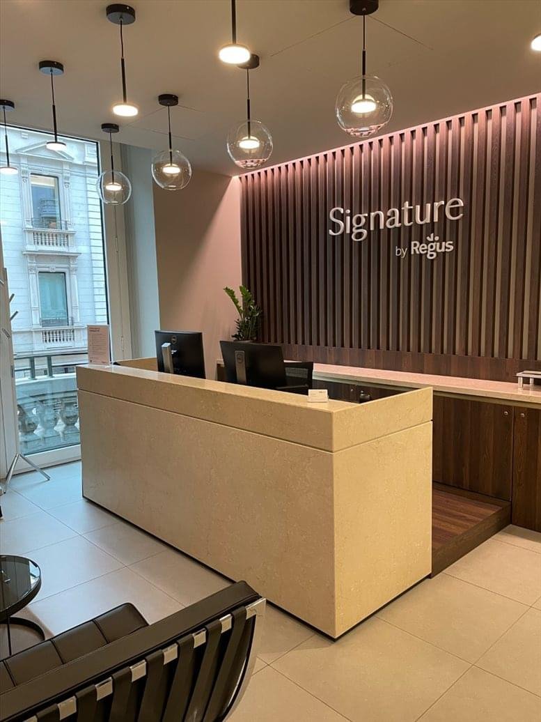 Modern reception area with a stone-textured desk and city views through large windows.