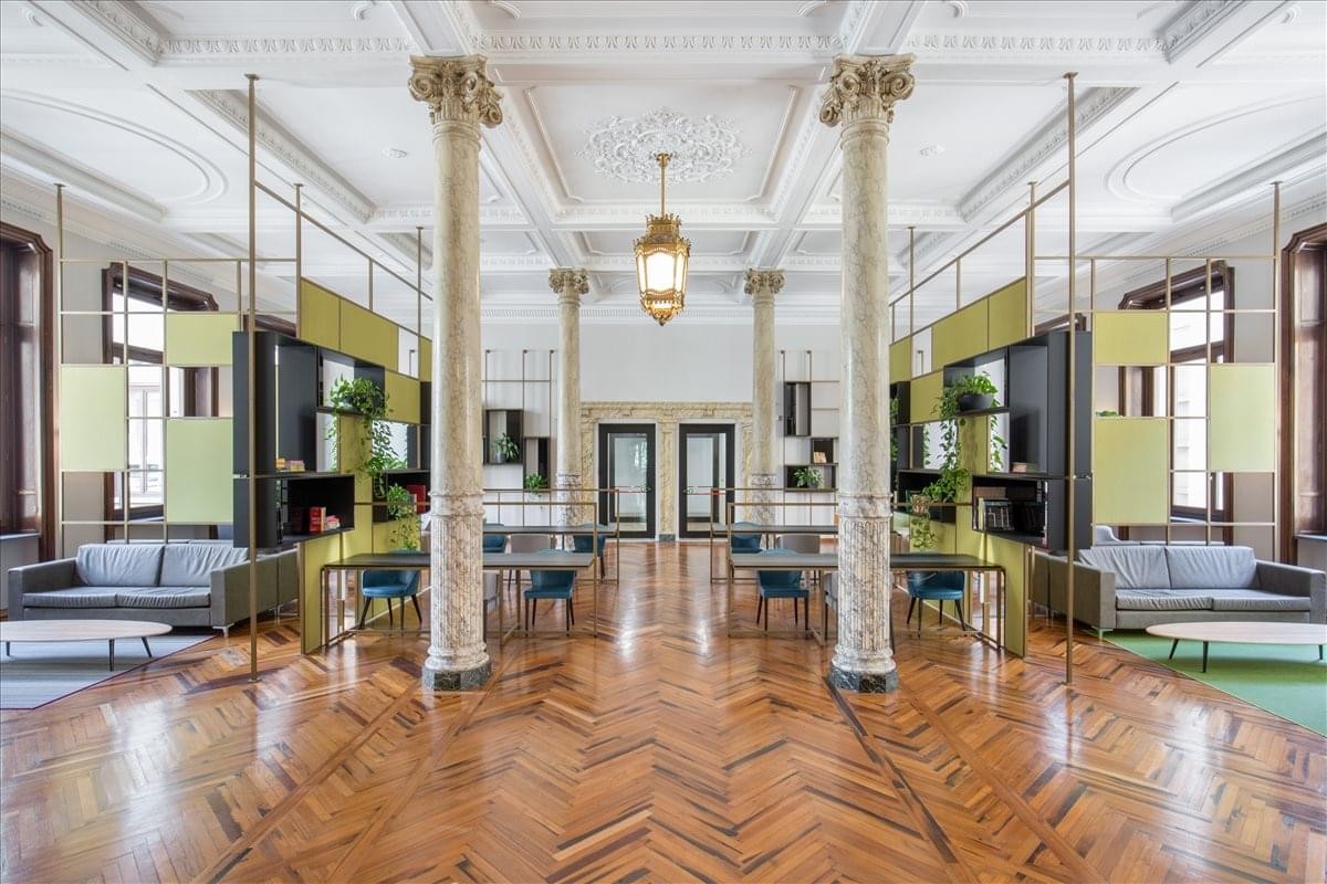 Corso Valdocco 2 interior featuring a grand lounge with marble columns and chevron wood floors.