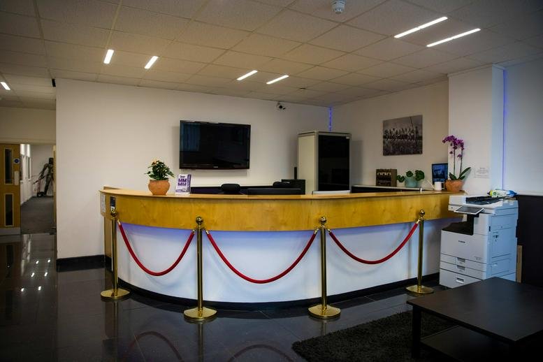 Reception desk at Cray Avenue, Orpington with curved wooden counter and red velvet rope stanchions.
