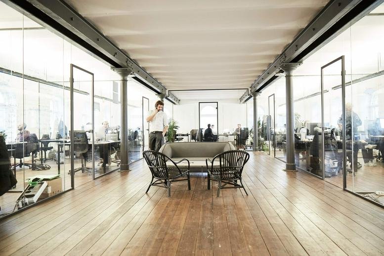Spacious, glass-walled office corridor at Danneskiold-Samsøes Allé 41 with lounge seating and wooden floors.