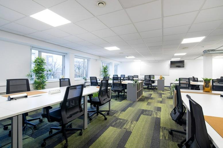 Spacious open-plan workspace at Desklodge House, Redcliffe Way, Bristol with modern desks and green patterned carpet.