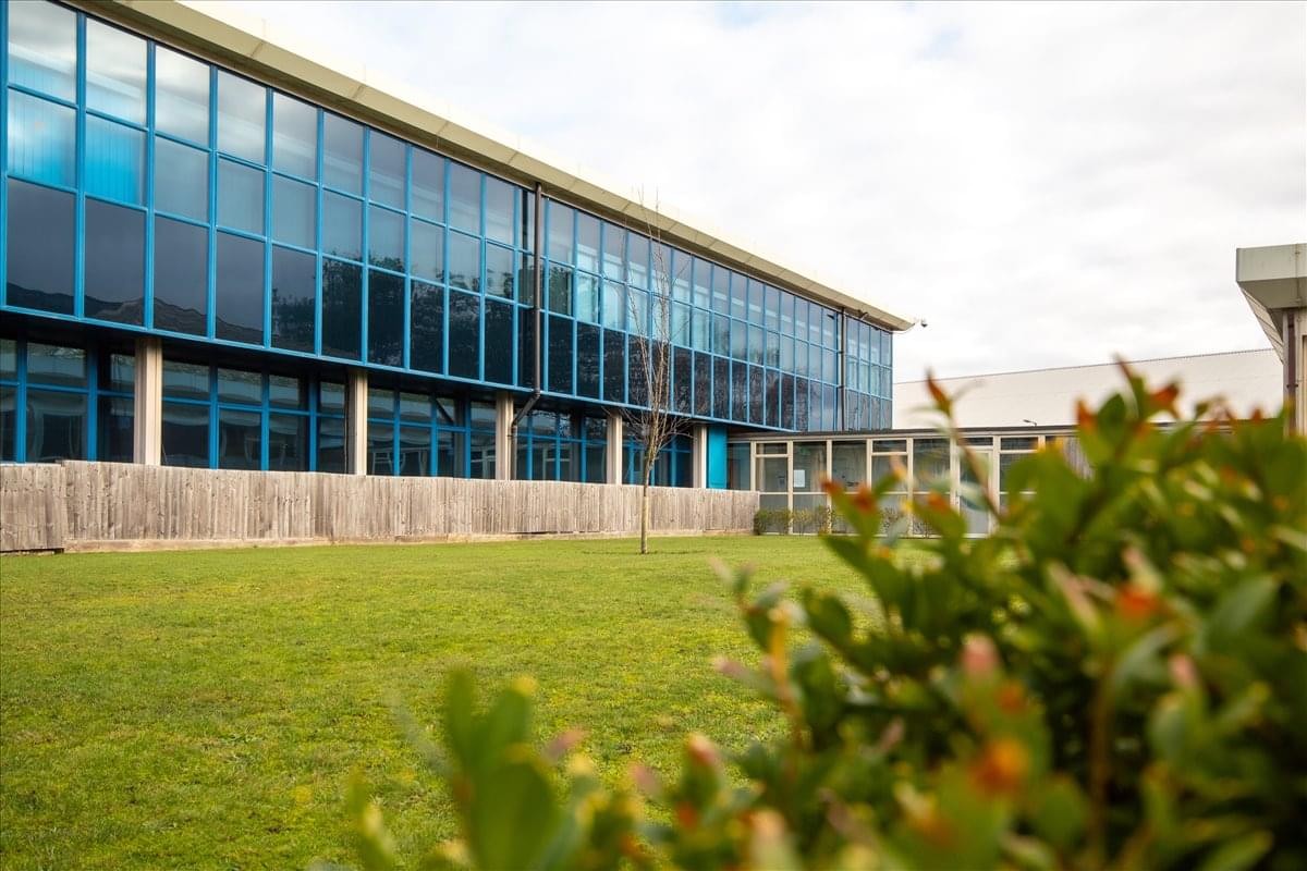 The glass-fronted modern facade of Discovery Court seen from the lush green lawn.