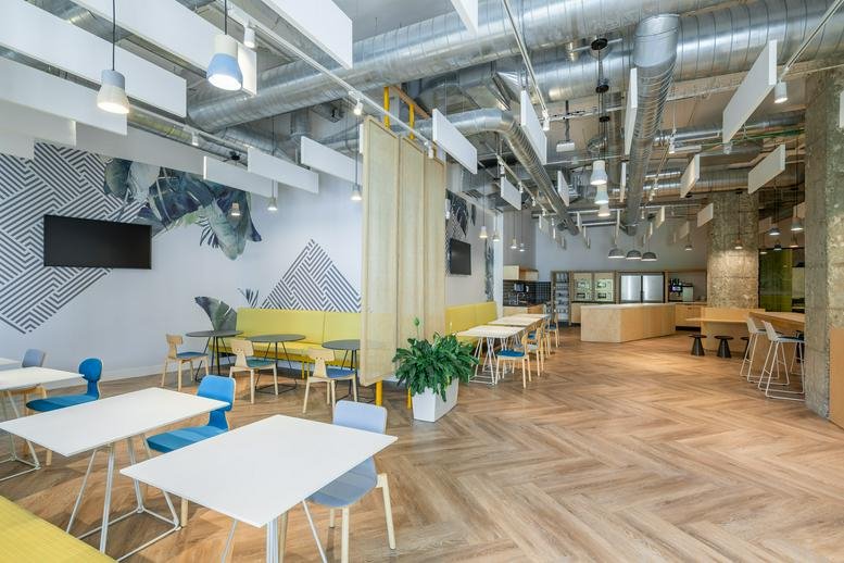 Spacious communal breakout area and cafe at Don Ramón De La Cruz, 84, Madrid with chevron wood floors.