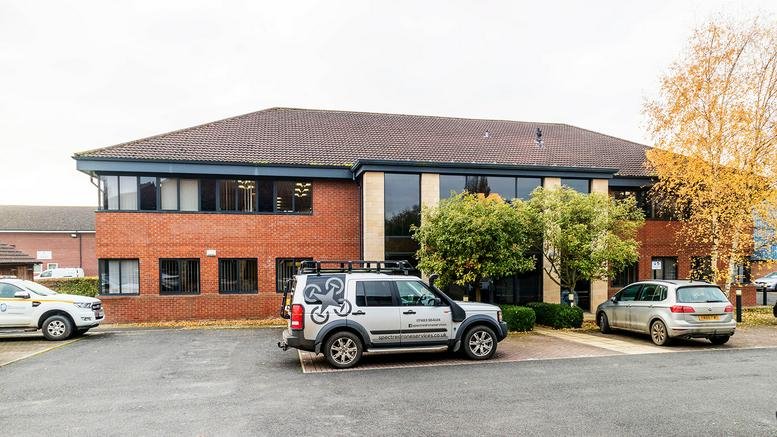 Exterior view of the brick facade at Easingwold Business Park with a parking area and trees.