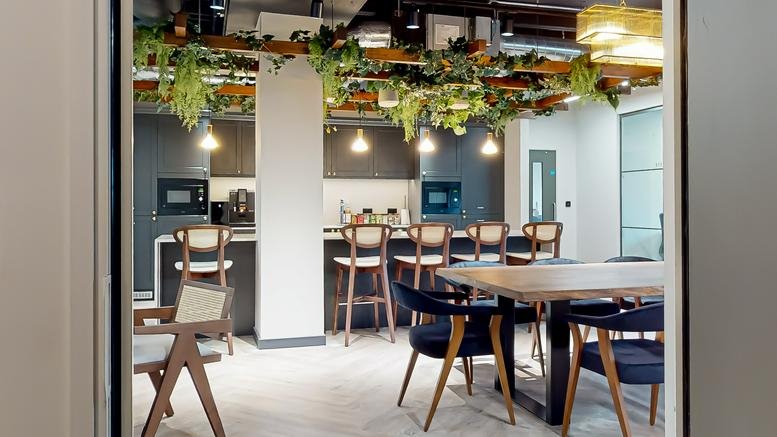 Wide view of a breakout space at Elder House, Milton Keynes, Buckinghamshire with greenery and dining tables.