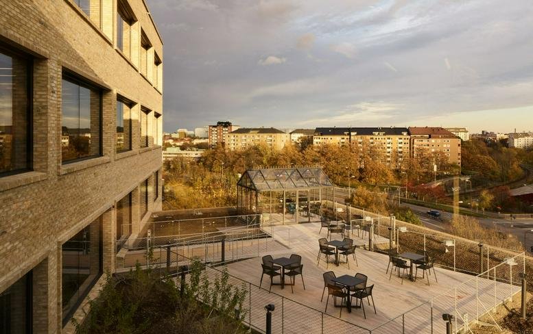 Exterior view of the modern brick facade at Elektrogatan 10, Solna, Sweden with a furnished roof terrace.