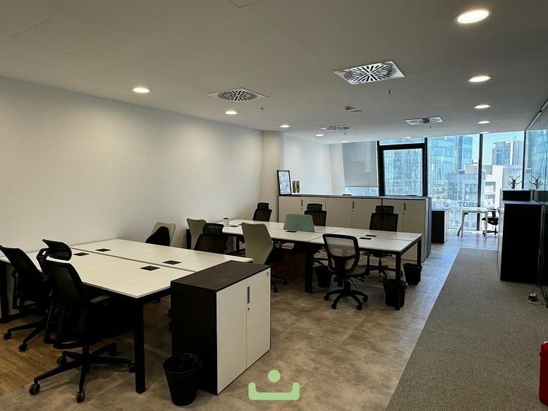 Spacious shared office area with multiple workstations and white storage cabinets.