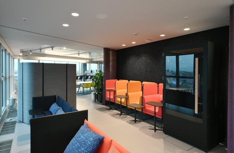 Spacious lounge at Europaplatz 2 with vibrant orange seating pods and a modern black privacy booth.