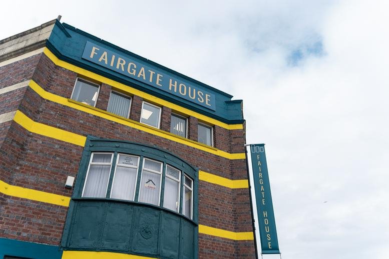 Exterior view of the brick facade of Fairgate House with yellow horizontal stripes.