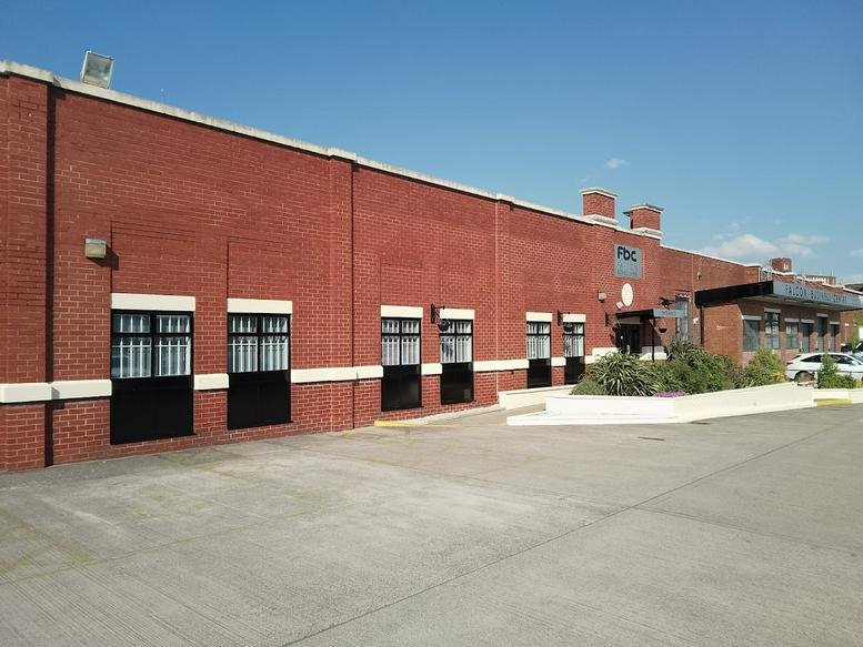 Wide-angle exterior view of the red brick building against a blue sky.