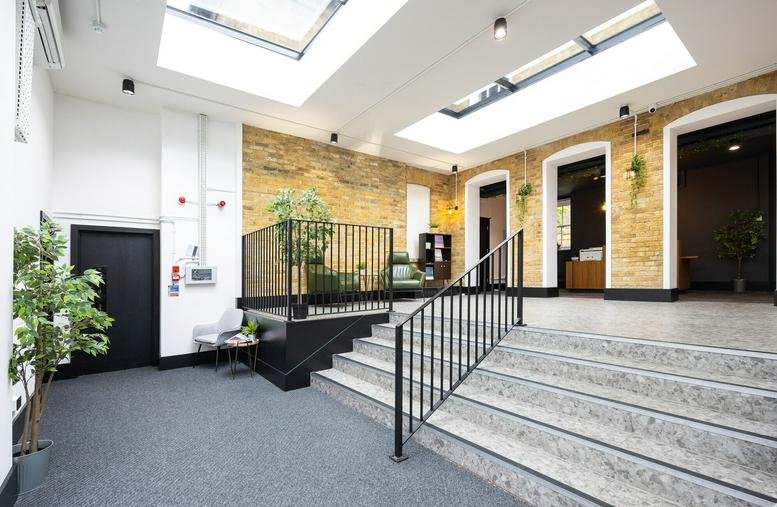 Spacious reception area with skylights, stairs, and exposed brick at the Former Magistrates Court.