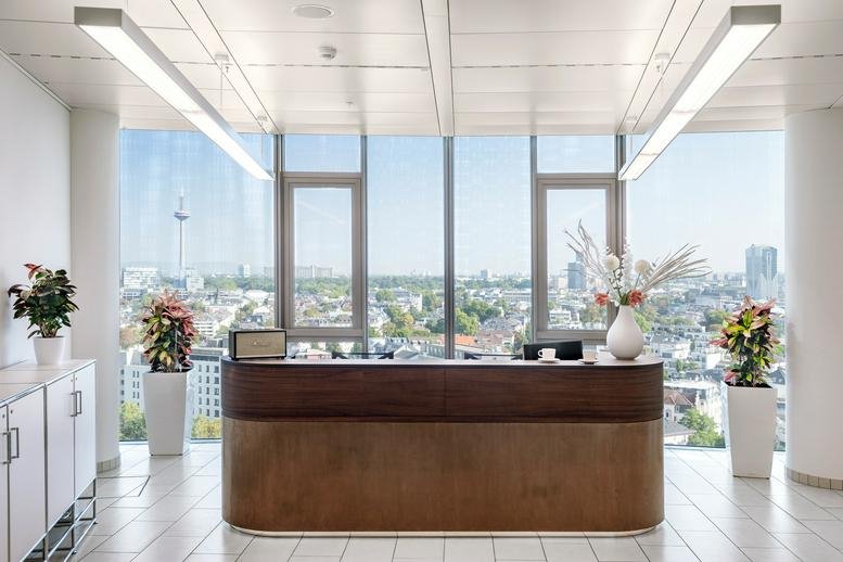 Elegant reception area at Friedrich-Ebert-Anlage 35, Tower 185 with wooden desk and floral arrangements.