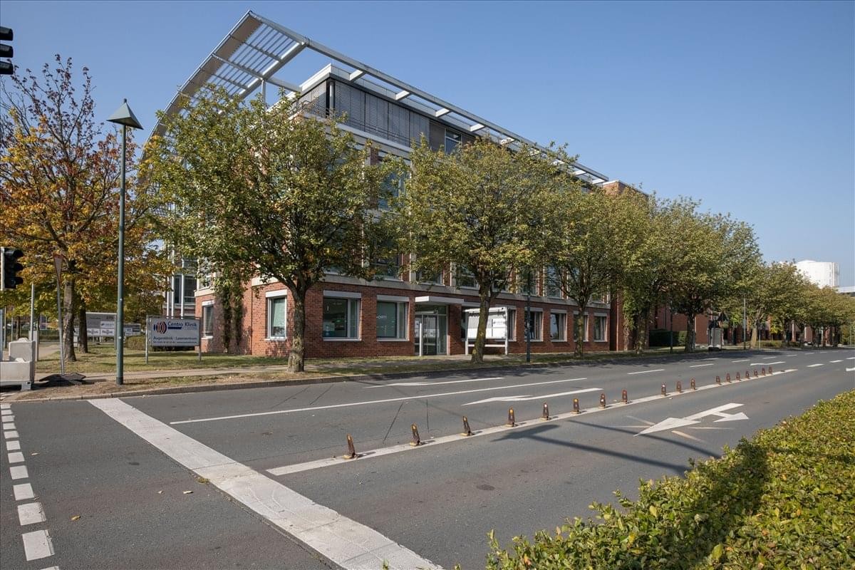 Modern multi-story office building exterior at Centroallee 273-277 with glass accents and mature trees.