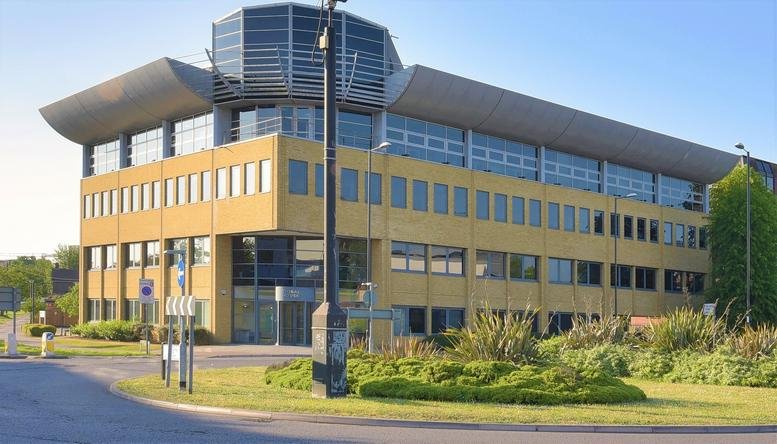Exterior view of the yellow brick Global House Business Centre featuring a unique curved roofline.