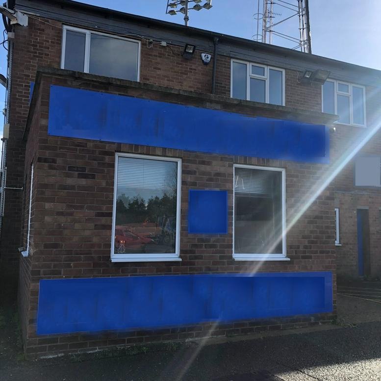 Exterior brick facade of Gloucester House, 23A London Road, Peterborough with large windows and blue branding panels.