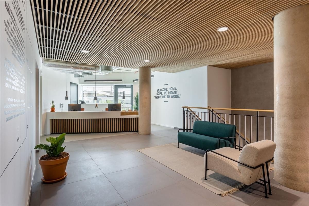 Spacious reception area with wood-slatted ceiling and teal sofa at Goodwin Street, Finsbury Park.