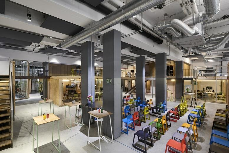Large open-plan workspace at Gotzinger Straße 8 featuring industrial ceilings and colorful furniture.