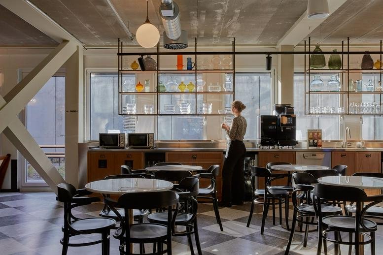 Spacious communal cafe area at Grünstraße 15 with hanging globe lights and industrial ceilings.