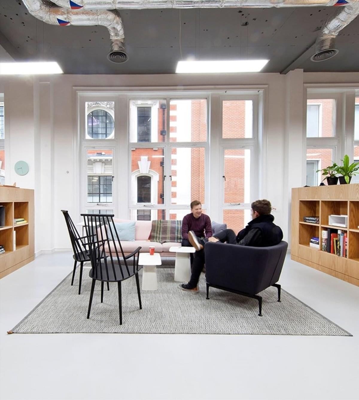 Common area at Gran Vía de les Corts Catalanes 583 with lounge seating, bookshelves, and large windows.