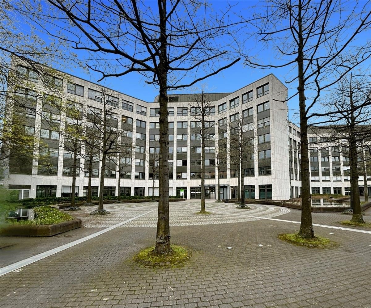 Wide exterior shot of the multi-story office building surrounded by mature trees.