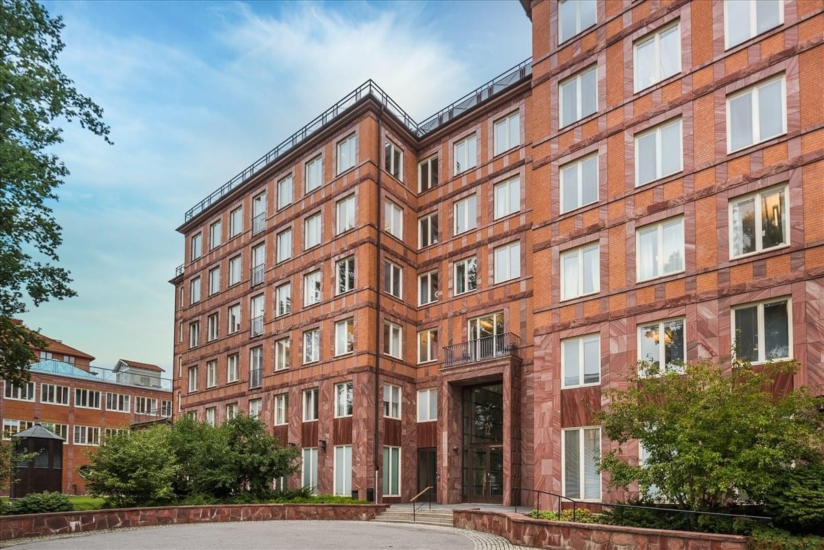 Exterior view of the red brick Gustavlundsvägen 12, Bromma building with large windows.