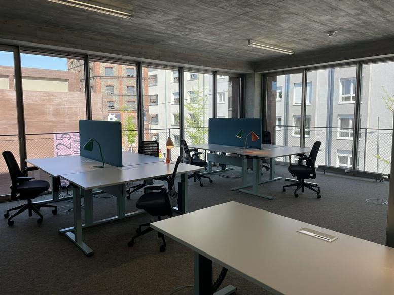 Spacious open-plan workspace at Hafenstraße 25-27 featuring modern sit-stand desks and large windows.