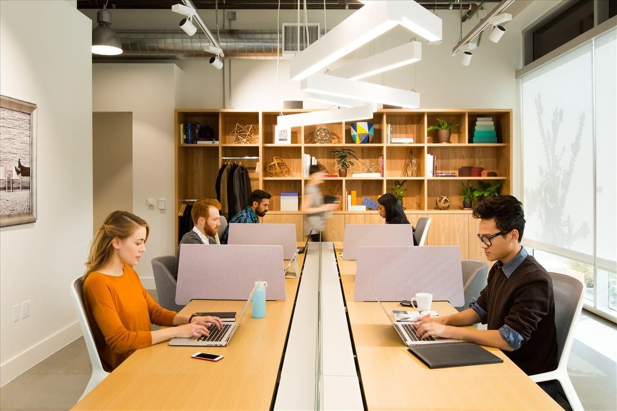 Spacious communal coworking area at Hammarbybacken 27 with long wooden desks and modern lighting.