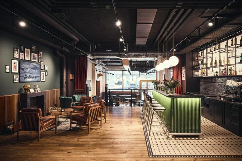 Lounge area with leather armchairs, fireplace, and green tiled bar at Hardturmstrasse 161, Hardturm, Zurich West.