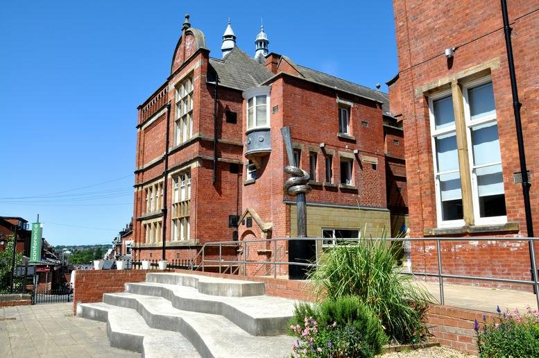 Exterior view of the red brick building at Harehills Road with outdoor tiered concrete seating.