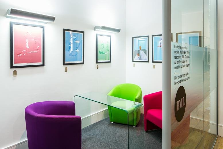 Small consultation room with colorful chairs and framed art on the wall.
