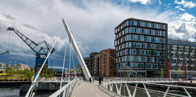 Modern architectural view of the office building next to a white pedestrian bridge.