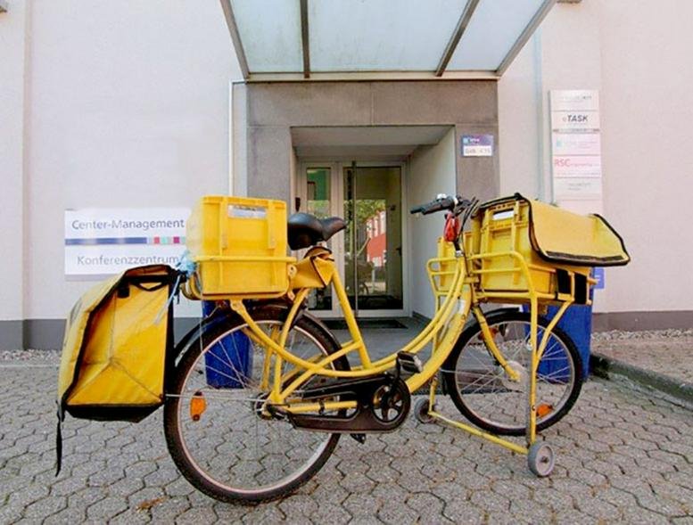 Entrance to the building at Herner Straße 299 with a yellow delivery bicycle parked outside.