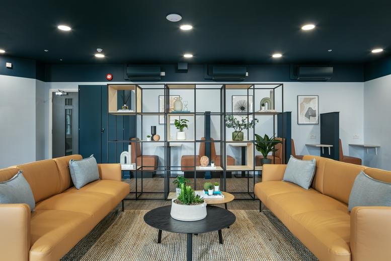 Spacious lounge at Hill Place House with leather sofas, dark ceilings, and a modern metal shelving divider.