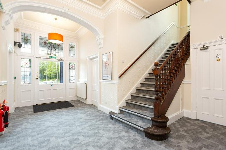 Grand entrance lobby of Hive Work Spaces, Viewfield Terrace, with a wooden staircase and arched doorway.