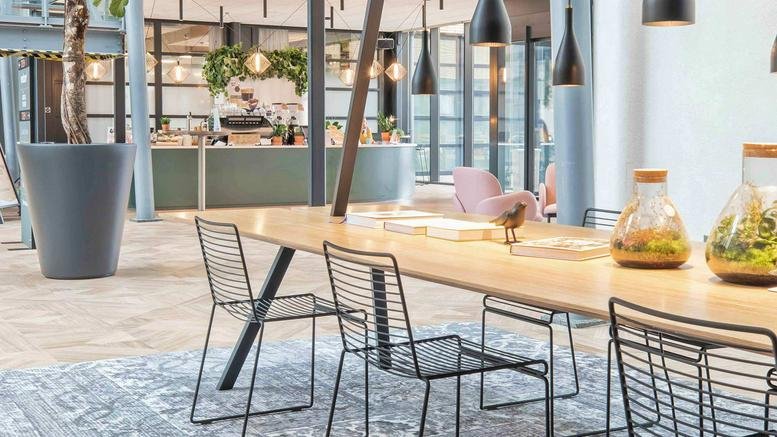 Spacious communal lounge at H. J. E. Wenckebachweg 123 with long wooden tables and indoor plants.