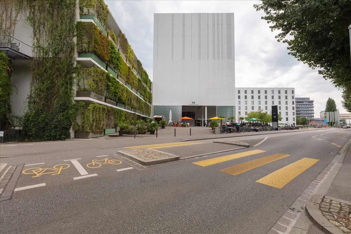 Exterior view of the white facade building at Hochbergerstrasse 70, Basel featuring a green living wall.