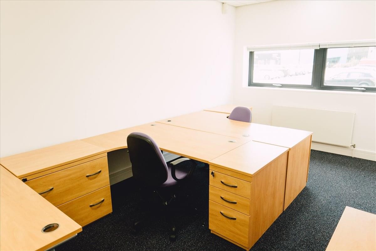 Private office space at Hollins Brook Park featuring two light wood desks, black chairs, and natural window light.