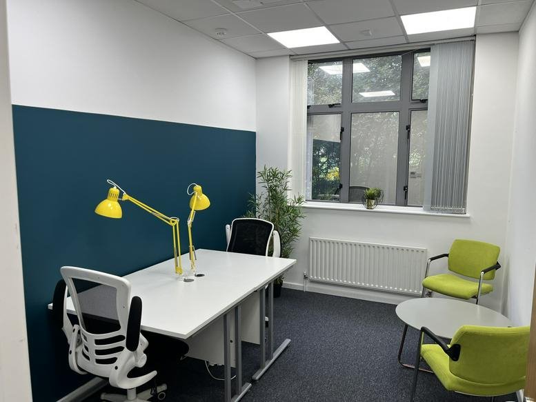 A modern workspace at Hope Park Workspaces @ Rooley Lane with a teal feature wall and yellow desk lamps.