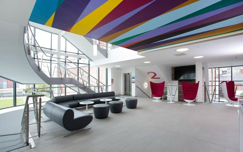 Spacious reception at Hope Street Xchange featuring a colorful striped ceiling and modern lounge seating.
