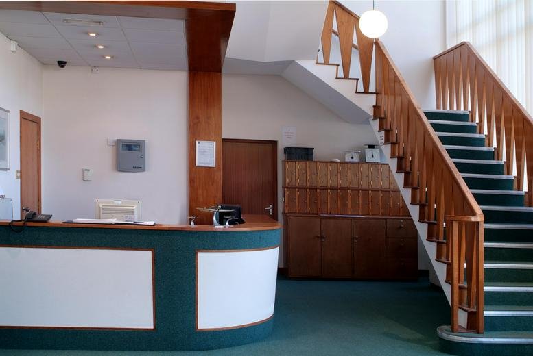 Spacious reception area at Hunts Rise, Berkeley House, featuring a curved desk and wooden staircase.