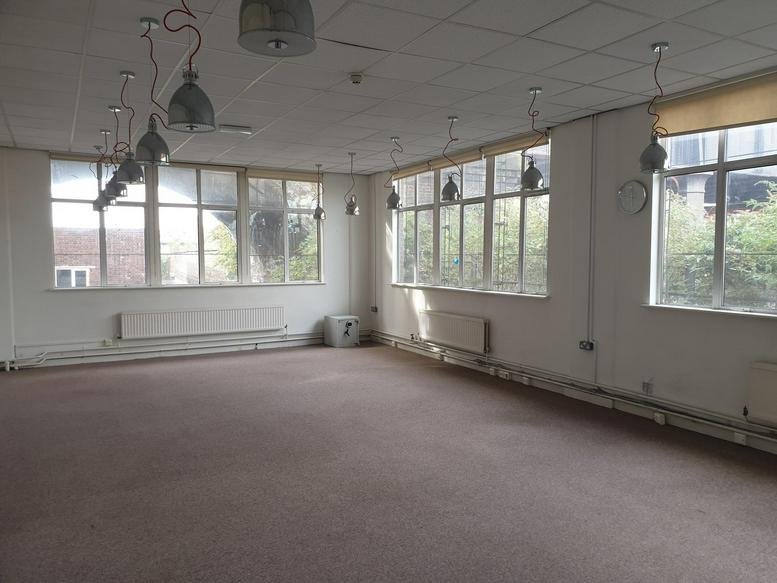 Large open-plan workspace with multiple windows and industrial-style pendant lighting.