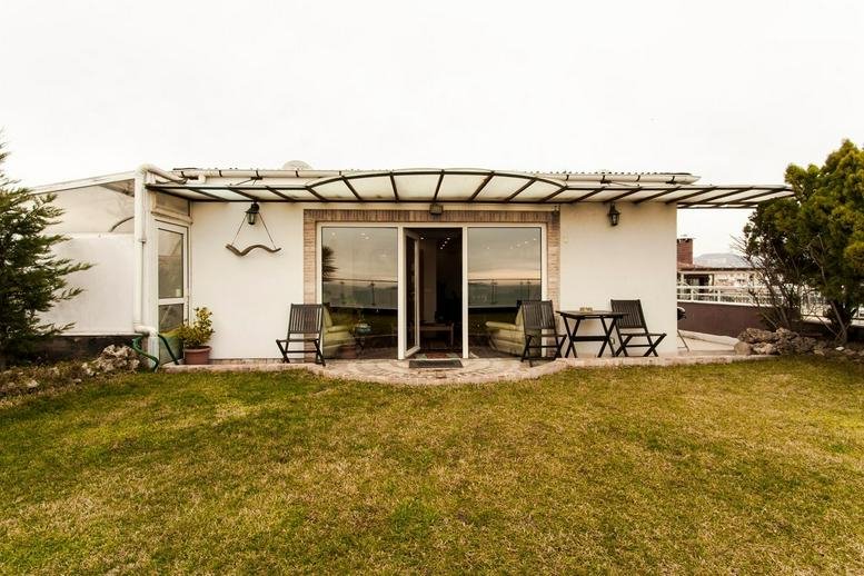 Exterior view of the white building at Istasyon Yolu Sk, 3, Altintepe with a paved patio and lawn.
