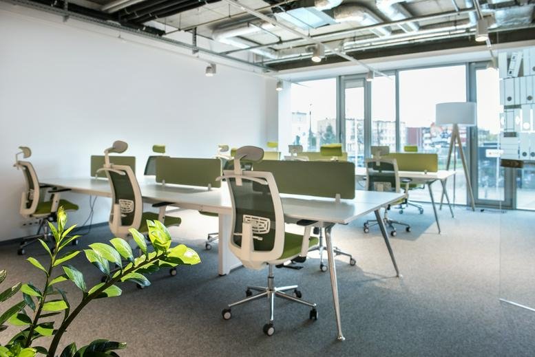 Spacious open-plan workspace at Jana Dekerta 24 with green ergonomic chairs and white desks.