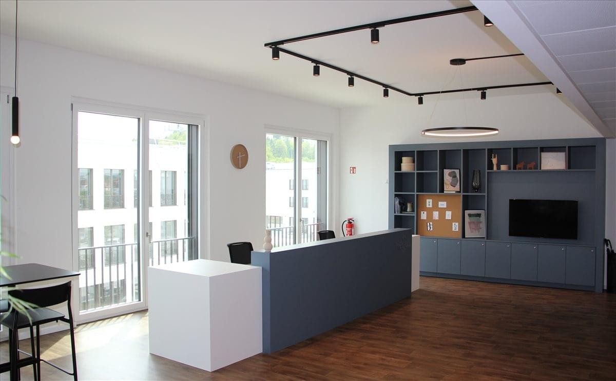 Professional reception area at Johanna-Kinkel-Strasse 1-2 featuring a sleek blue desk and warm wood flooring.