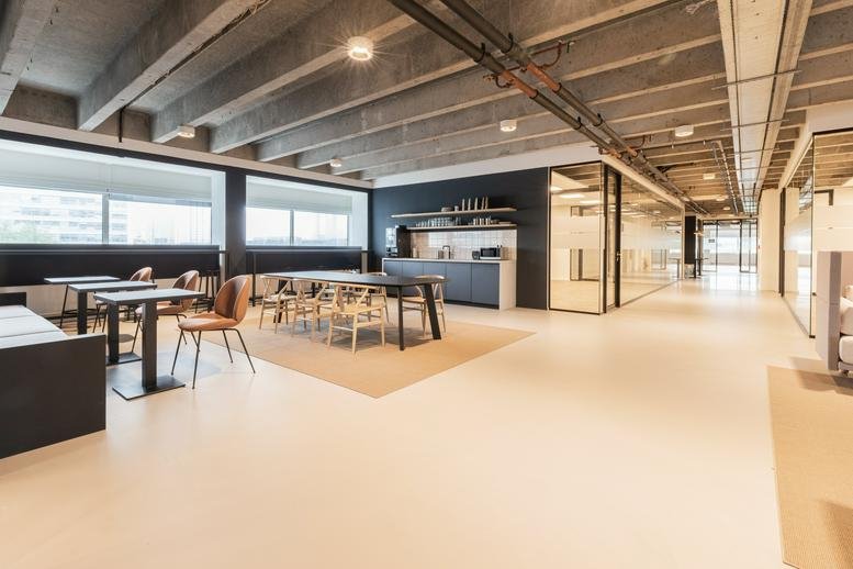 Spacious communal lounge and dining area with industrial concrete ceilings at Kabelweg 37.