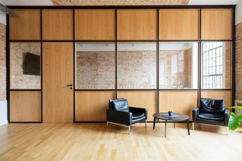Spacious communal lounge at Kastanienallee 84 with wood paneling and black leather armchairs.