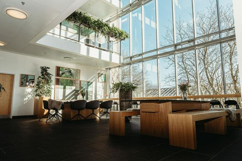 Spacious communal dining area with long wooden tables and a floor-to-ceiling glass wall.