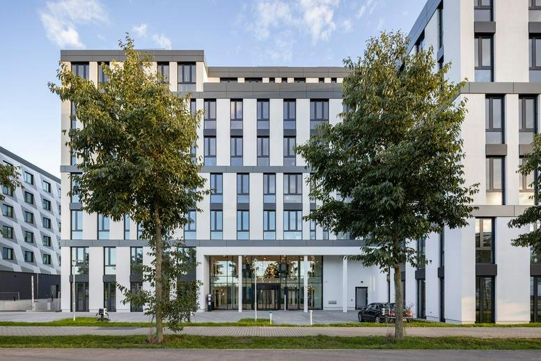 Exterior view of the white and grey modern facade of the Kienberger Allee 4 building.