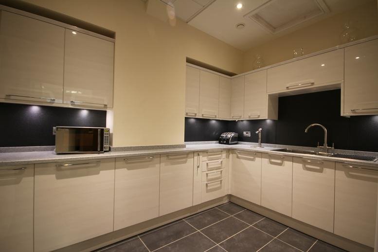 L-shaped kitchen with white cabinetry and dark countertops.